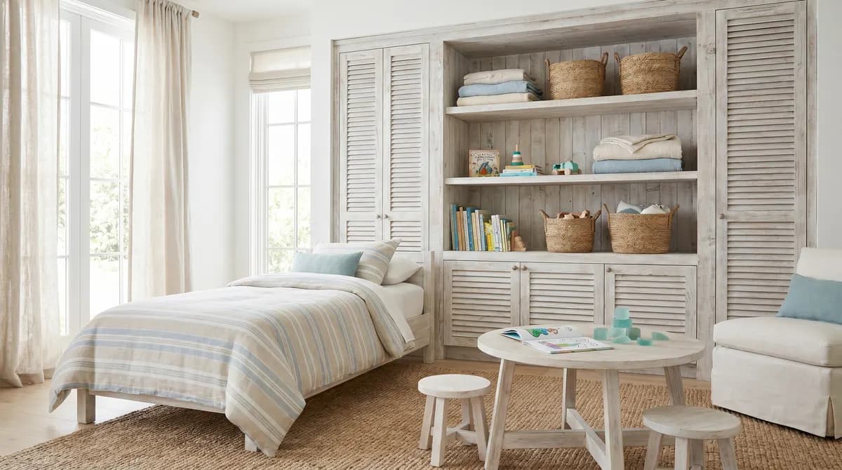 White spindle twin bed with linen duvet and blue-and-white striped quilt