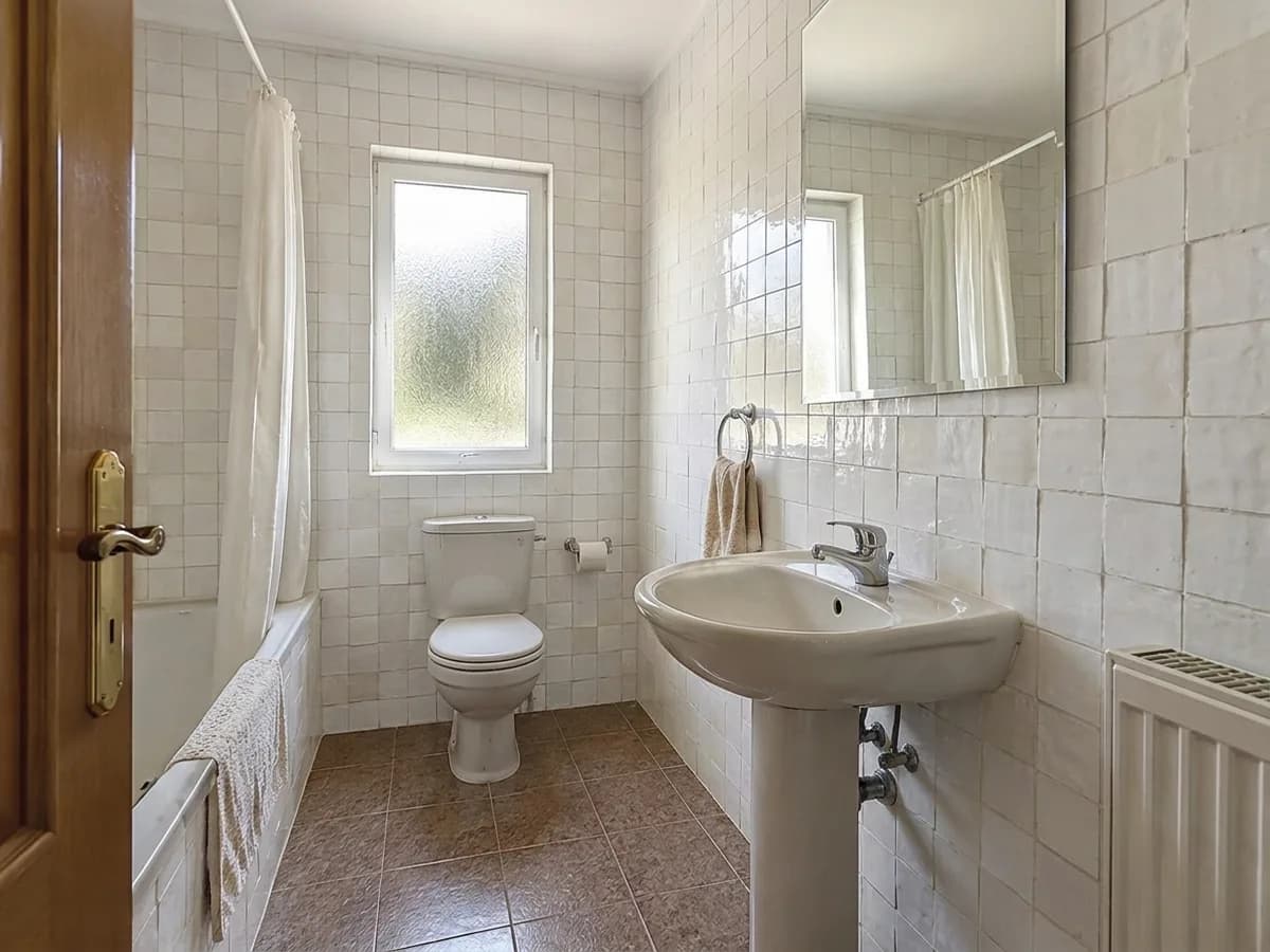 The same bathroom with white zellige on the walls and the original brown floor tiles